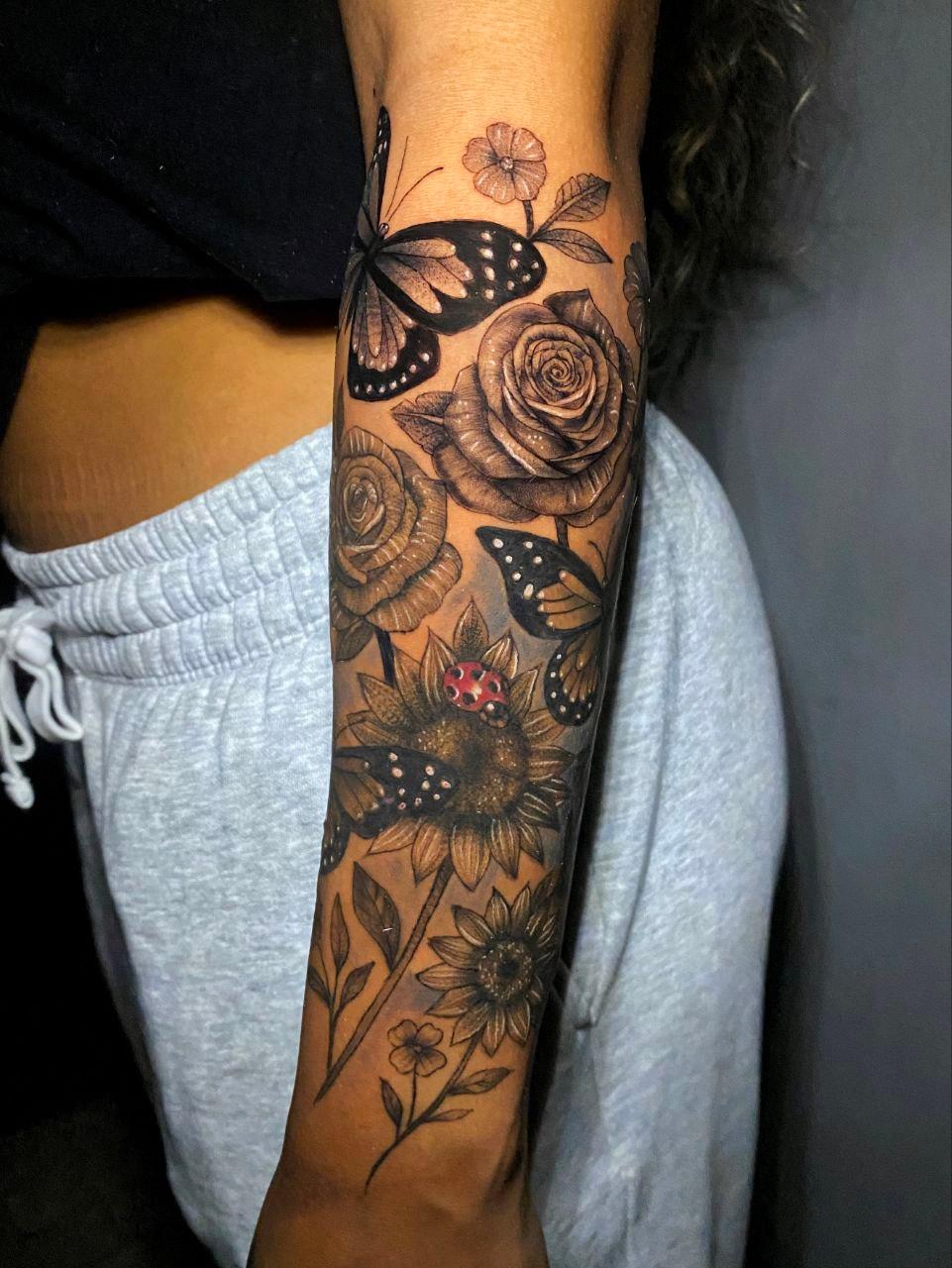 Tatuaje floral con girasoles, mariposas y una mariquita