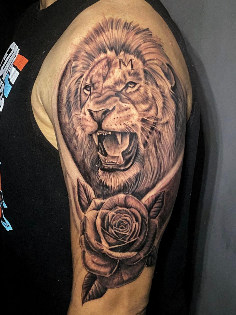 Tatuaje realista de león rugiendo con una rosa en el brazo