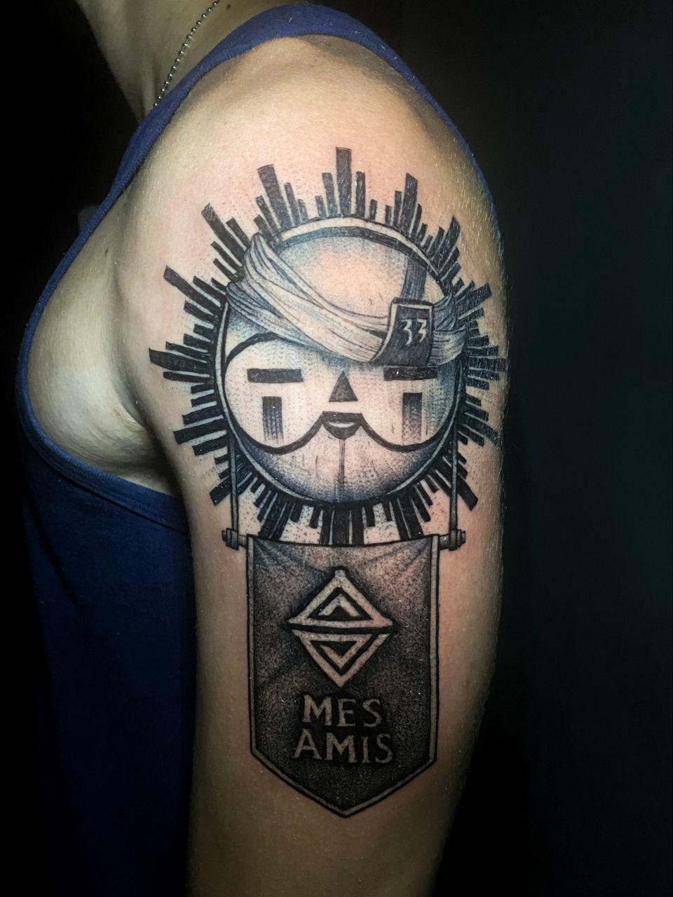 Tatuaje blackwork con emblema y rayos, texto MES AMIS