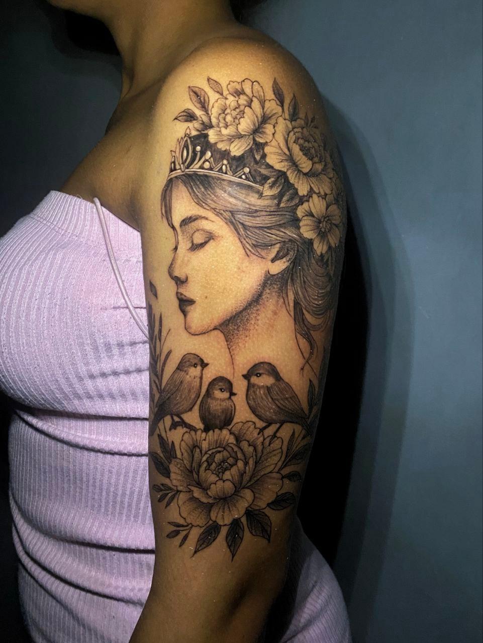 Tatuaje realista de mujer coronada con flores y aves