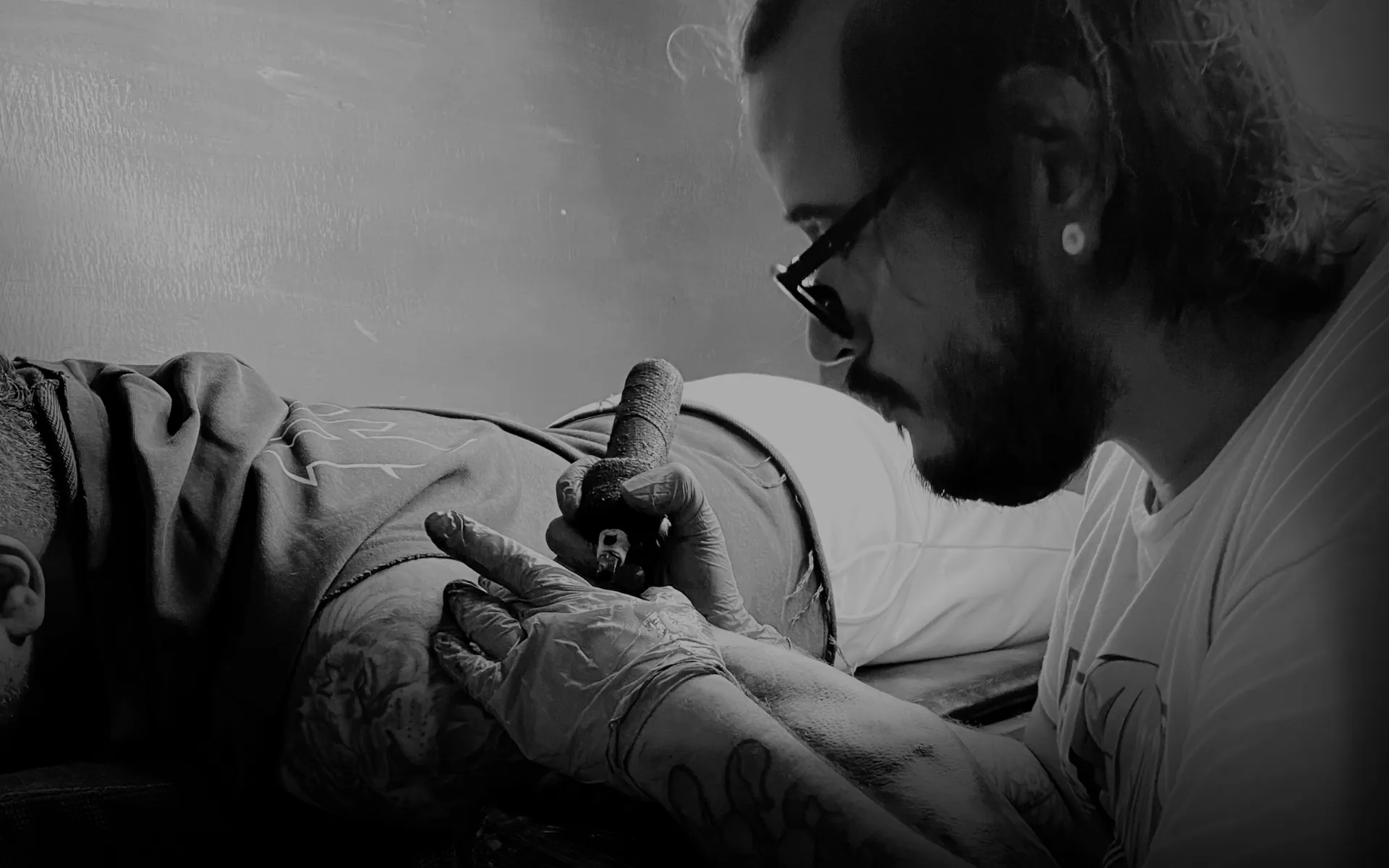 Carlos Quintero tatuando en un ambiente íntimo y oscuro
